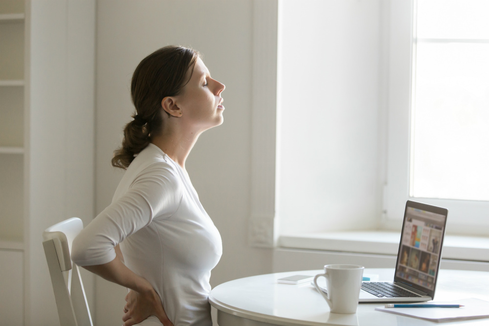 Woman experiencing pain sitting at desk